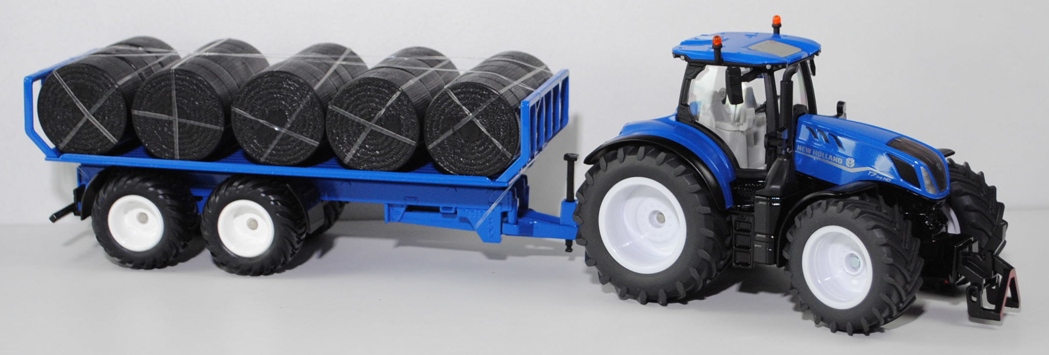 00700 IE + GB New Holland T7.315 HD AC New Generation (Modell 2021-) mit Rundballenanhänger, blau/schwarz, Ladegut: Rundballen schwarz, SIKU FARMER 1:32, L17mpK (Limited)